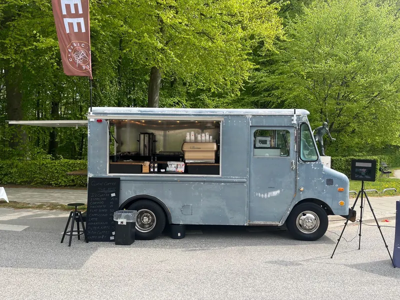 Kaffebilen Prince, en grå kaffevogn med åbent skod i en grøn skov